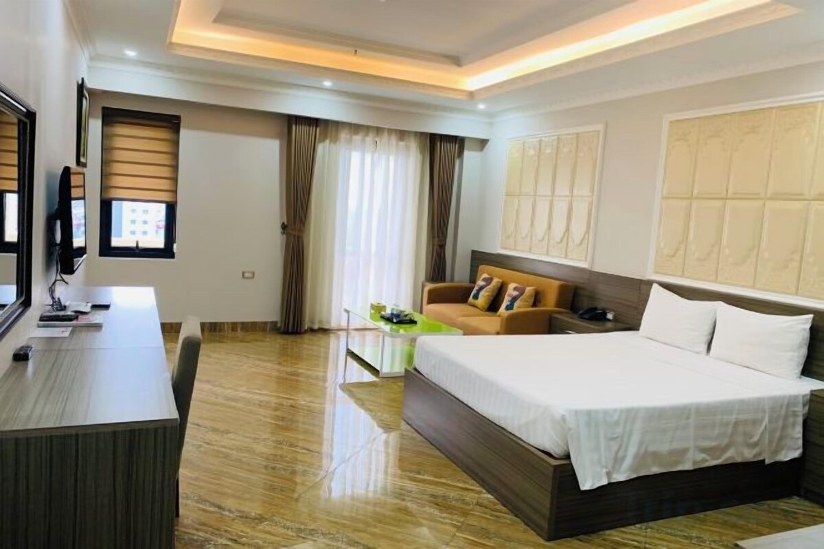 A hotel room with a bed, a desk, and a TV.
