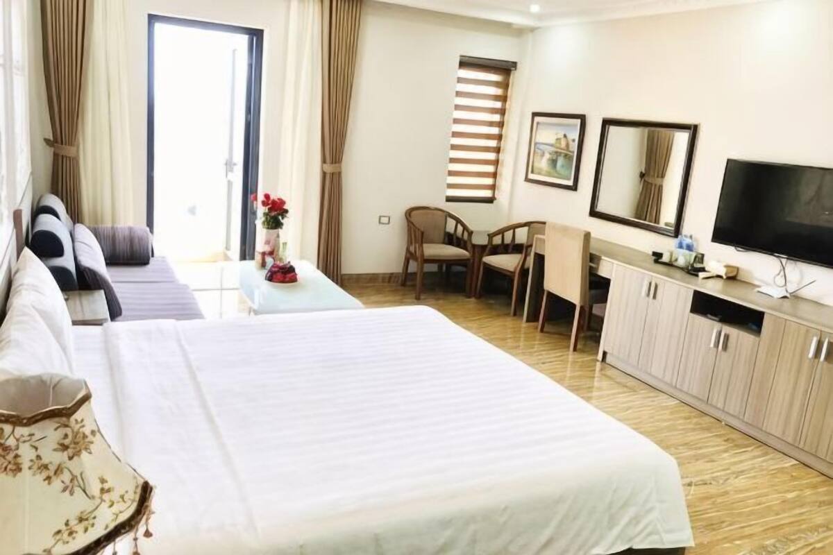 A hotel room with a bed, a desk, a chair, a television, and a window with curtains.