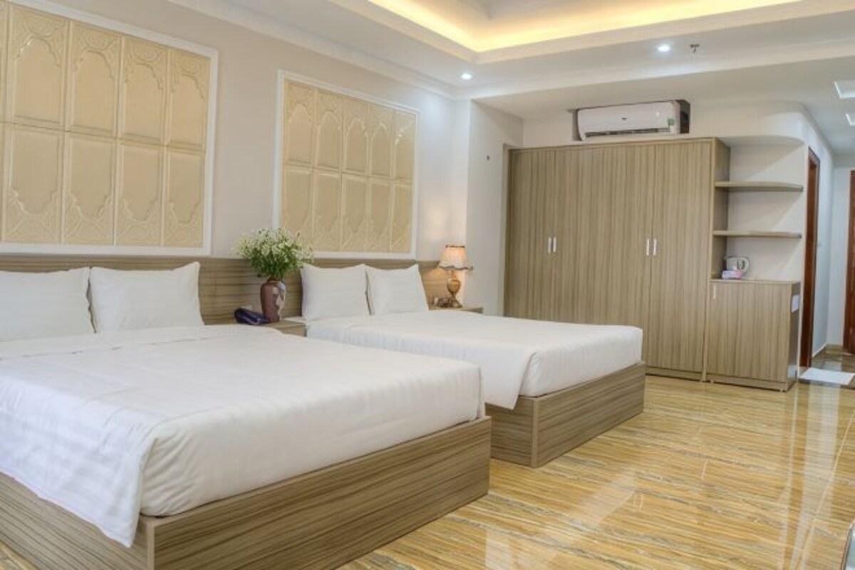 Habitación de hotel con dos camas, un armario, un escritorio y una planta.
