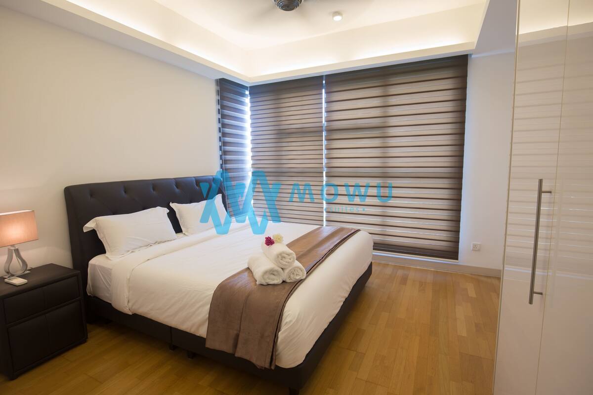 Une chambre moderne avec un grand lit, une table de chevet, une lampe et une fenêtre avec des stores.