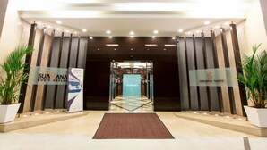 A hotel entrance with a modern design, featuring a glass door and a sign for 'Suanana Suites'.