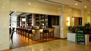 A bar area with a counter and multiple stools, a reception desk, and a sign indicating the bar is open.