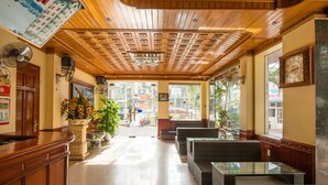 Un vestíbulo con techo de madera, zonas de estar y una recepción.