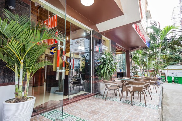 A restaurant with outdoor seating, a large potted plant, and a Wi-Fi sign.