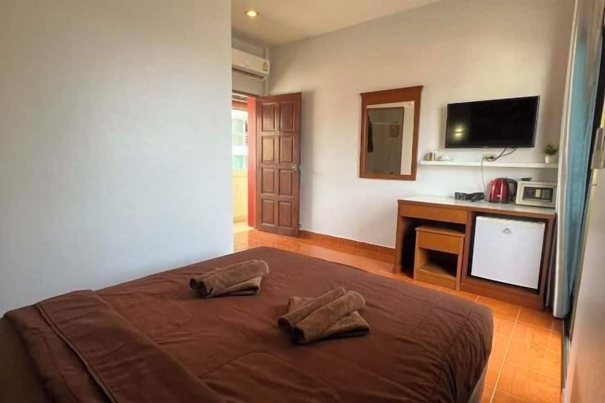 A hotel room with a bed, a desk, a television, and a small refrigerator.