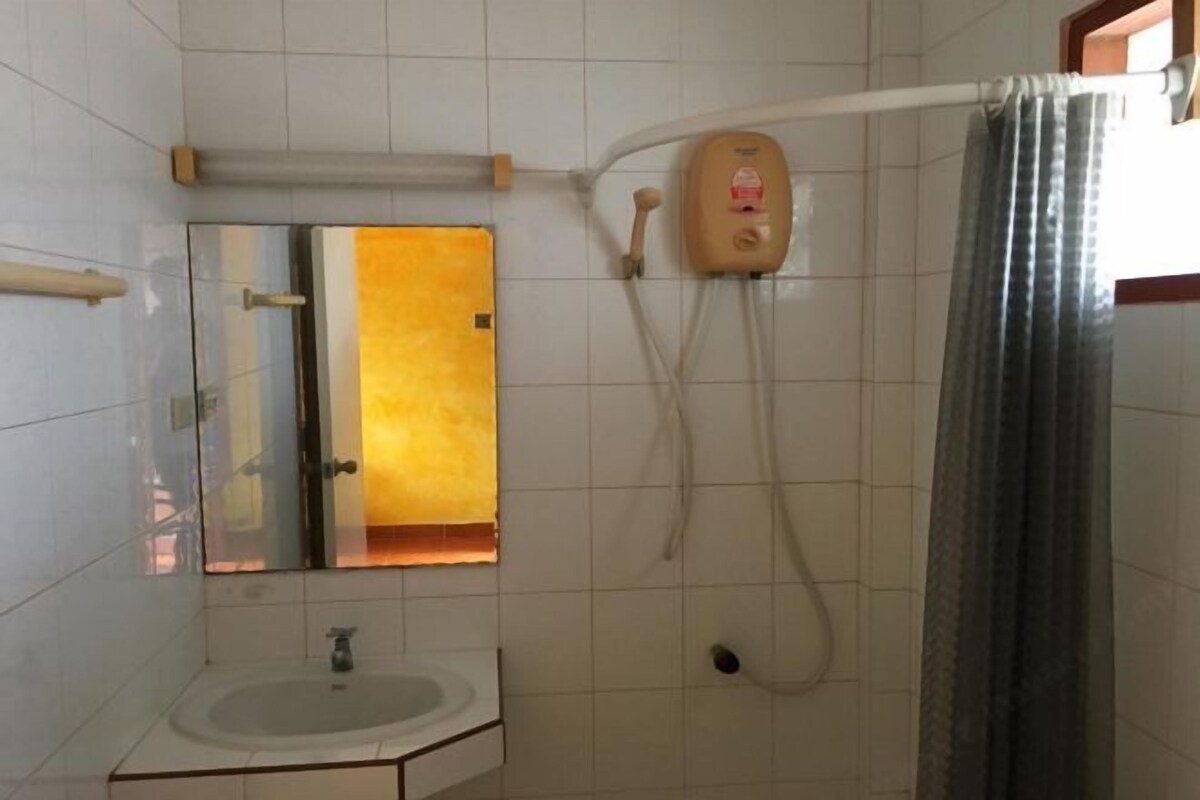 Un baño con lavamanos, espejo, ducha y toallero.
