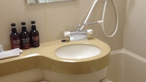 A bathroom with a toilet, sink, and bathtub. There are three bottles of shampoo on the counter. - Business Hotel Kamoshita (Mito)