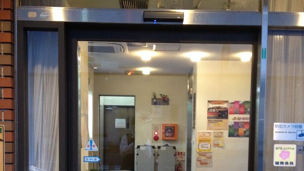An entrance with a glass door, a fire extinguisher, and a sign on the wall. - Business Hotel Kamoshita (Mito)