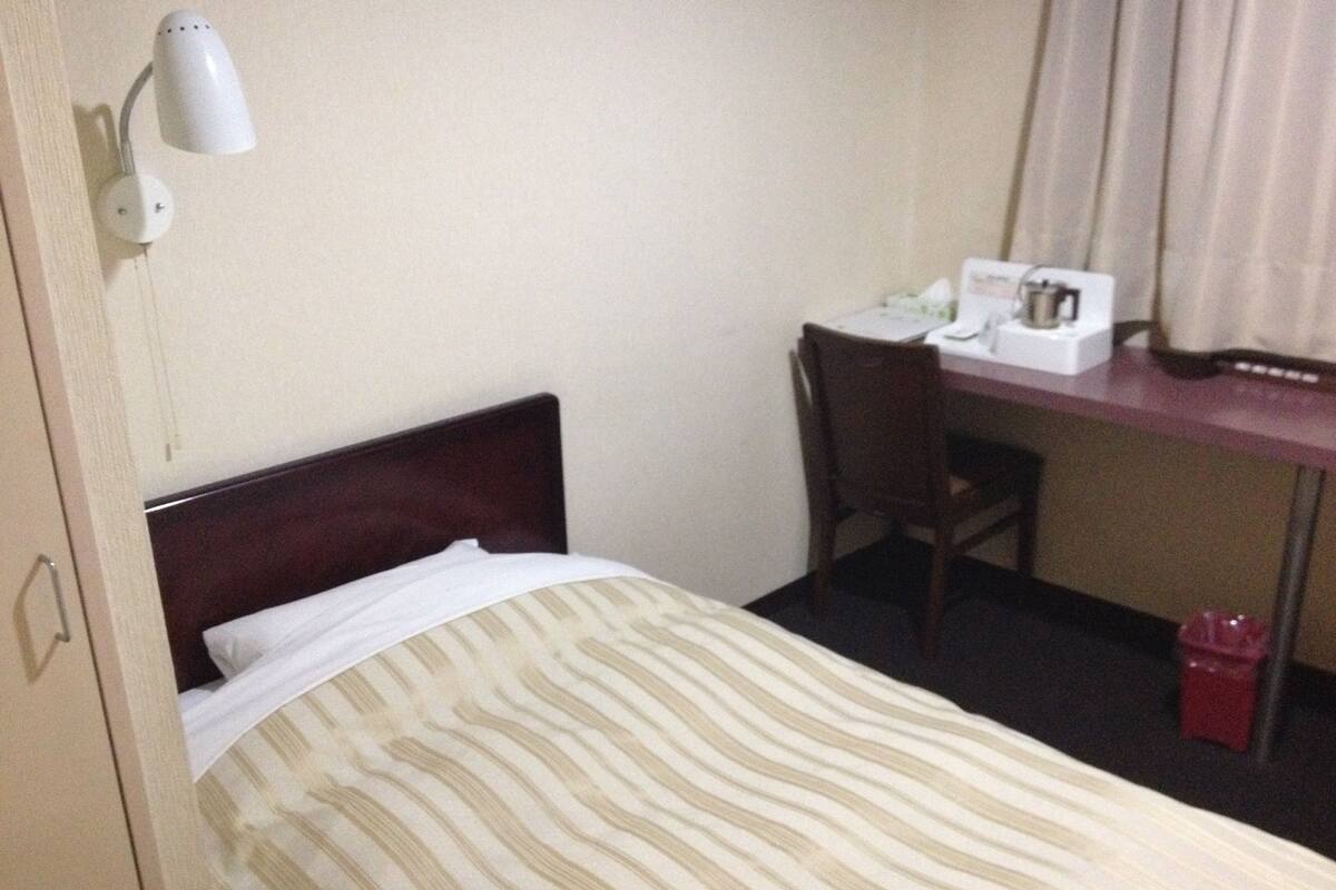 Ein Hotelzimmer mit einem Bett, einem Schreibtisch, einem Stuhl und einer Schreibtischlampe.