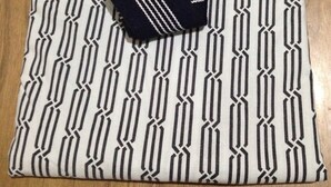 A neatly folded bedspread with a geometric pattern, placed on a wooden floor. - Business Hotel Kamoshita (Mito)