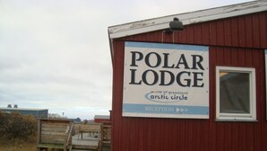 Un edificio rojo con un letrero que dice "Polar Lodge" y "Recepción", indicando una zona de recepción.