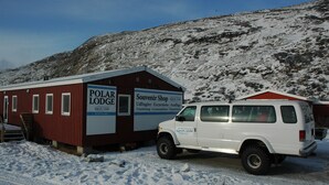 Un edificio rojo con la leyenda 'Polar Lodge', y una camioneta blanca estacionada frente a él.