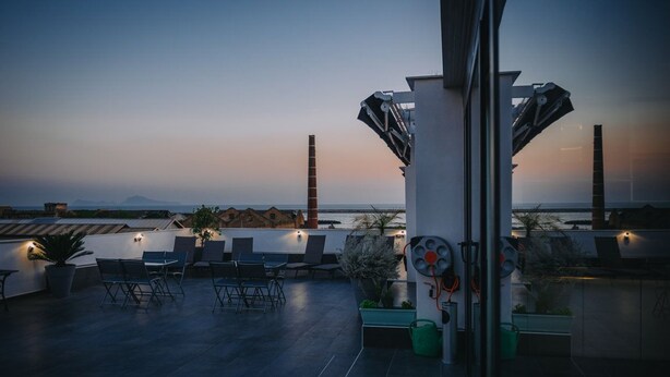 Terraza en la azotea con mobiliario y vista al mar al atardecer.