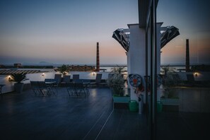 A rooftop terrace with seating and a view of the sea at dusk. - Palazzo San Vincenzo (Naples)