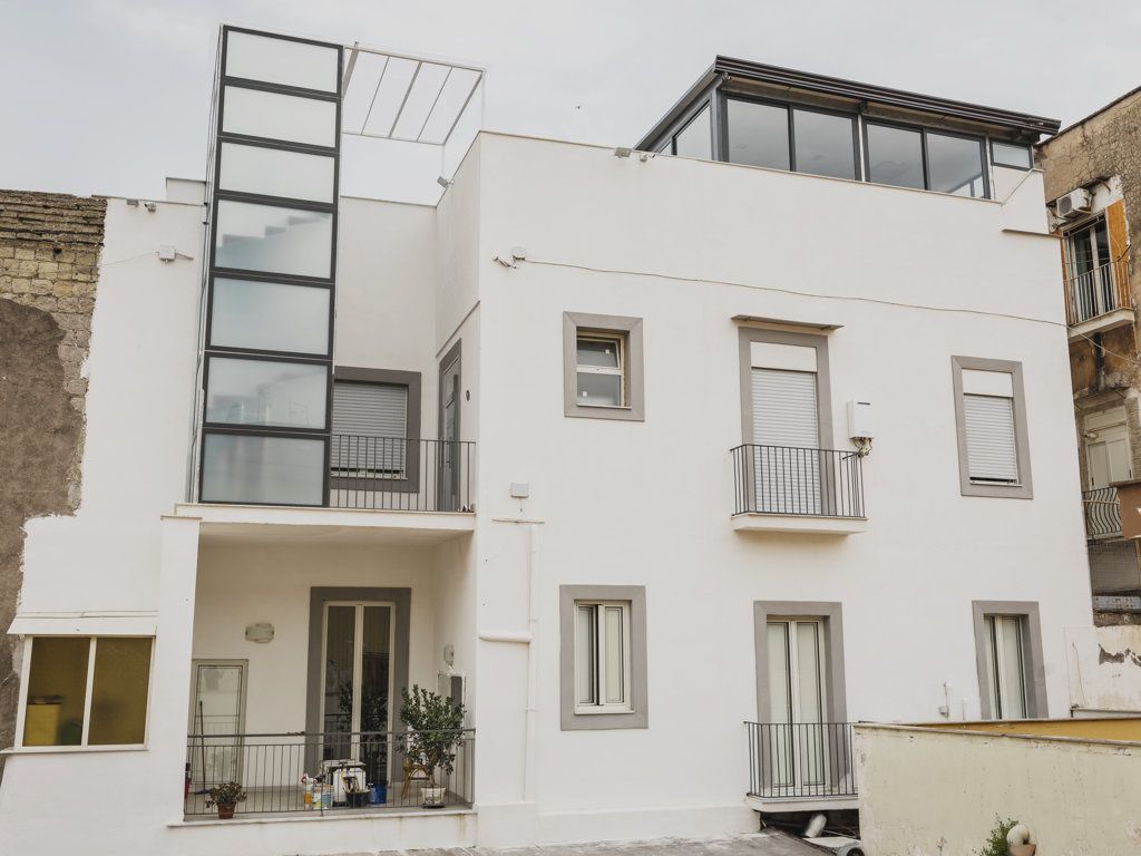 Un edificio moderno a più piani con balconi, un ingresso al piano terra ben visibile e un tetto piatto.