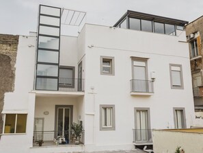 A modern multi-story building with balconies, a visible ground floor entrance, and a flat roof. - Palazzo San Vincenzo (Naples)