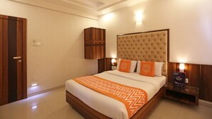 A hotel room with a large bed, a ceiling fan, and a nightstand with a lamp. - Hotel Satyan Inn (Rahata)