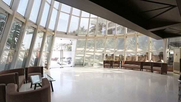 A spacious lobby with a high ceiling and large windows, modern furniture, and a clean, polished floor. - Hotel Satyan Inn (Rahata)