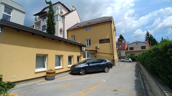 A residential building with a sign reading "ANTUNOVAC" and a parked car in the driveway.
