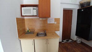 Eine kleine Küche mit Mikrowelle, Spüle und Holzschränken.