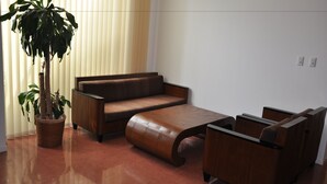 Una sala de estar con un sofá marrón, una mesa de centro de madera y una planta en maceta.