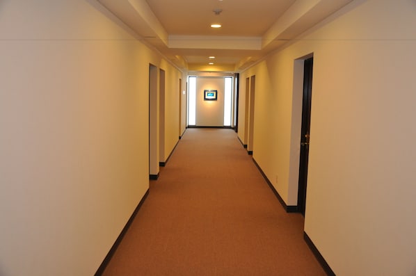 Un largo y estrecho pasillo de hotel con piso alfombrado y puertas a ambos lados.