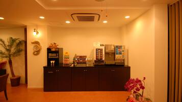 A reception area with a counter, coffee machines, a microwave, and a decorative wreath.