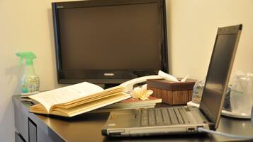 Un escritorio con una laptop, un libro abierto, un atomizador, una caja de pañuelos y un monitor.