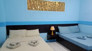 A hotel room with a bed, a nightstand, a lamp, and a decorative wall panel. - Hayward Travel Inn (Tacloban)