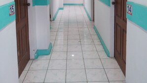 A corridor with white walls and teal trim, featuring doors numbered 14 and 15. - Hayward Travel Inn (Tacloban)