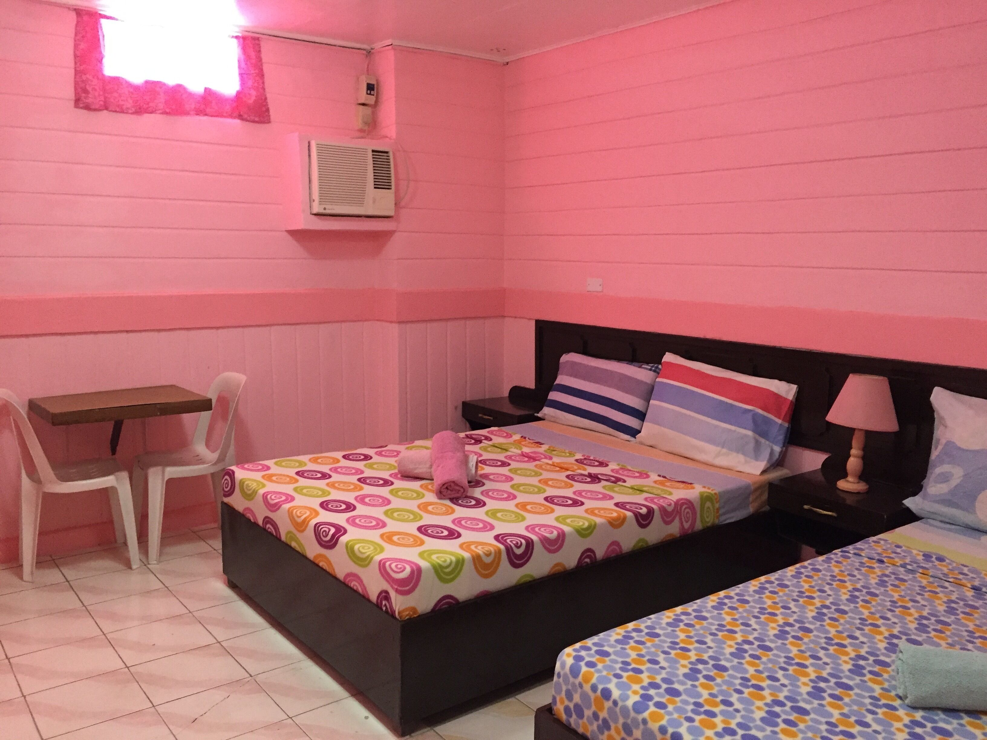 A pink-themed bedroom with a bed, a desk, and a chair.