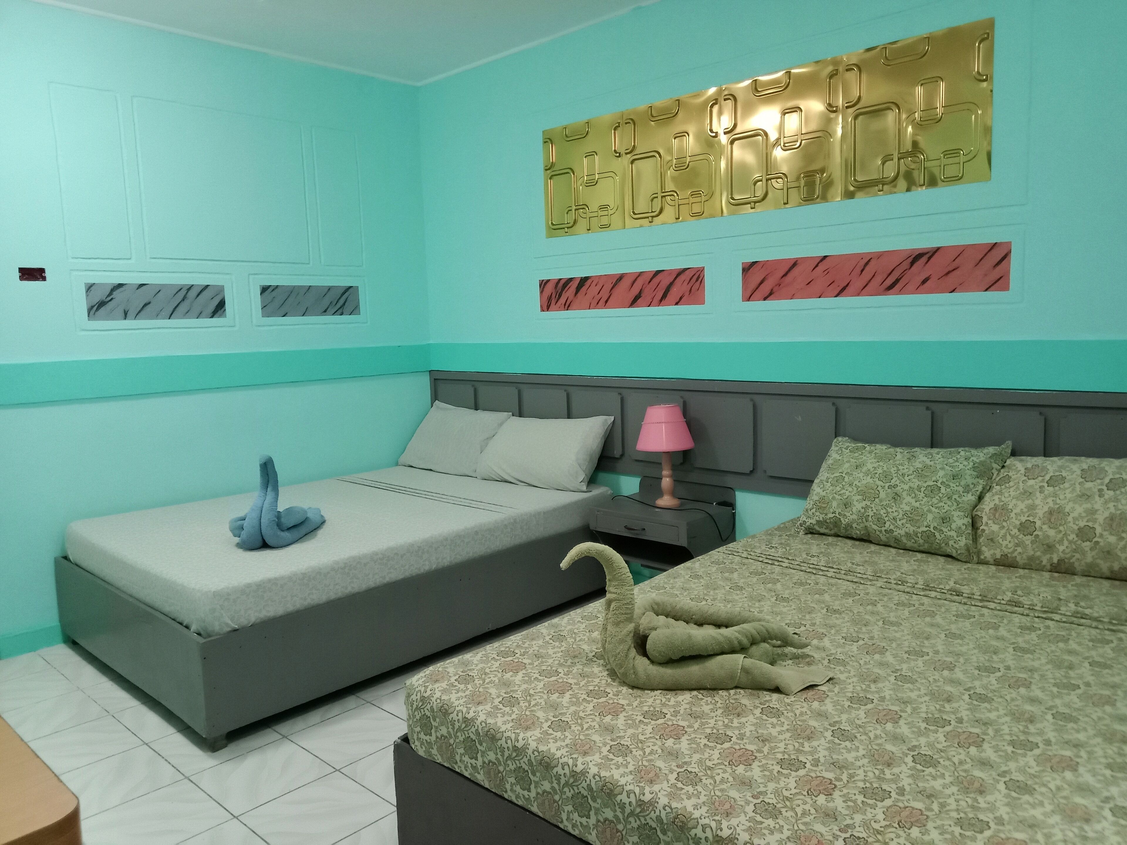 Une chambre avec deux lits, une table de chevet, une lampe et un panneau décoratif mural.