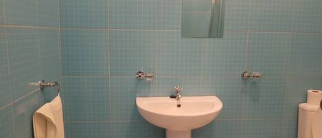 A bathroom with blue tiles, a white sink, and a toilet.