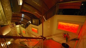 Ein modernes Interieur mit einer geschwungenen Treppe, einer großen beleuchteten Wand und einem Blumentopf.