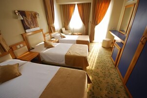 Quarto de hotel com duas camas, uma mesa, uma cadeira e um espelho.