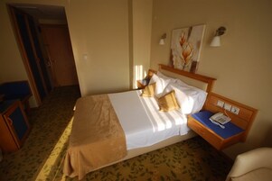 Una habitación de hotel con cama, mesita de noche y una silla.