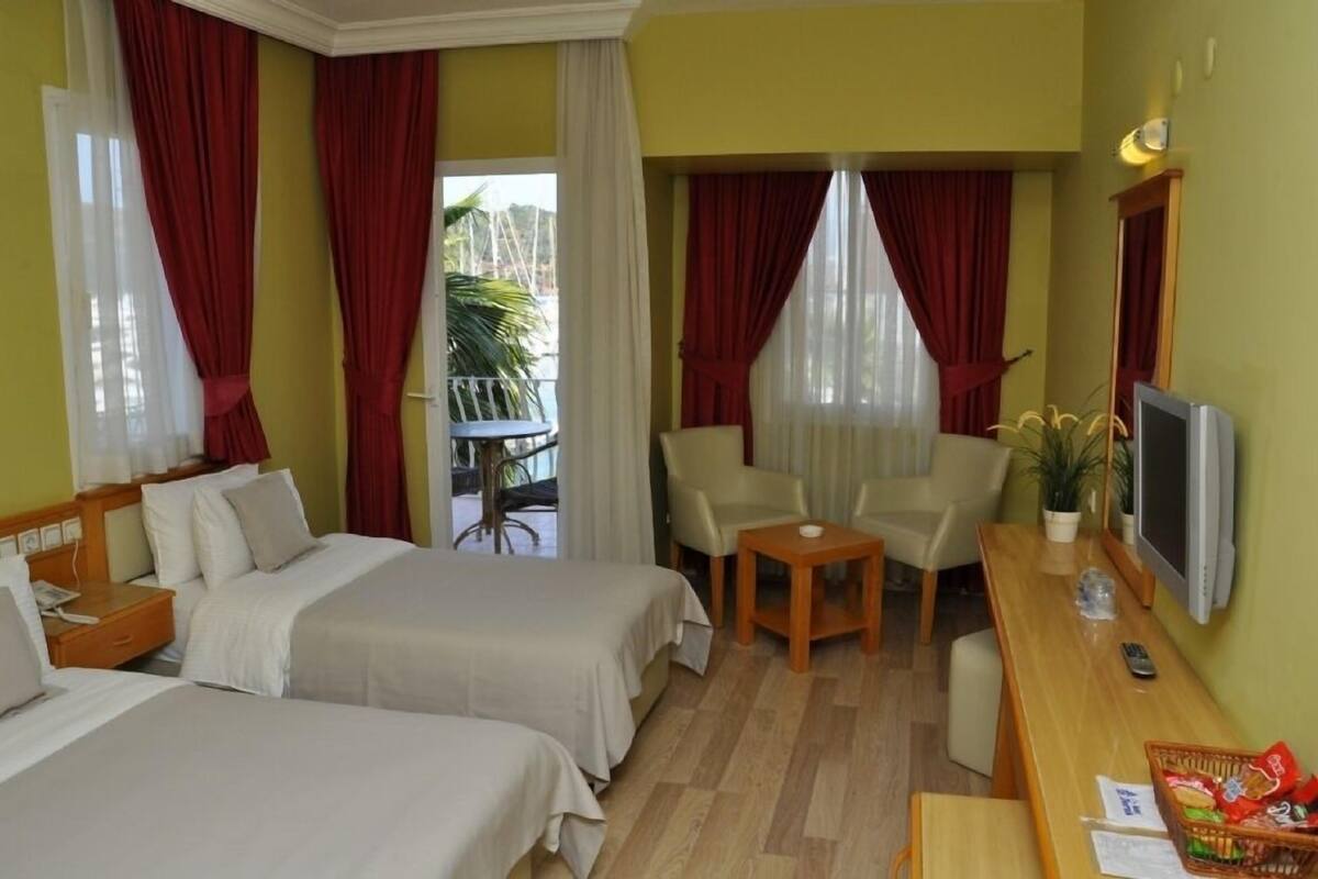 A hotel room with two beds, a desk with a TV, a chair, and a small table.