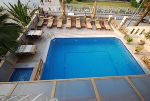 A rooftop pool area with lounge chairs and a small table. - Hotel Doruk (Fethiye)
