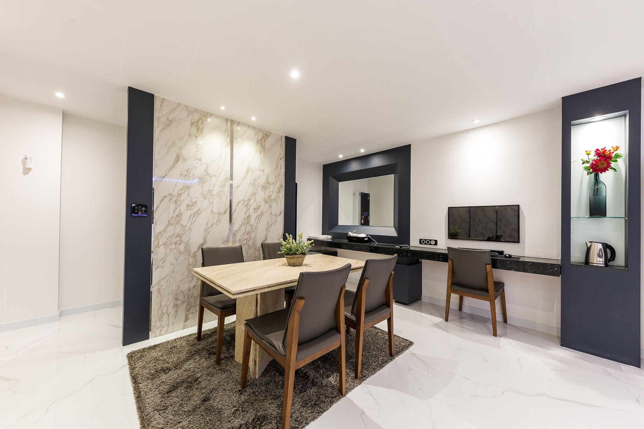 A modern dining area with a marble wall, a wooden table, and chairs.