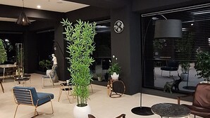 A spacious lobby with modern furniture, a large potted plant, and a view through the window.