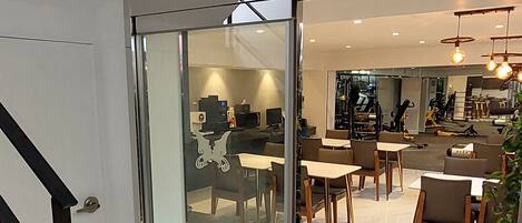 Un interior moderno con una puerta de cristal que da a un comedor con mesas y sillas.