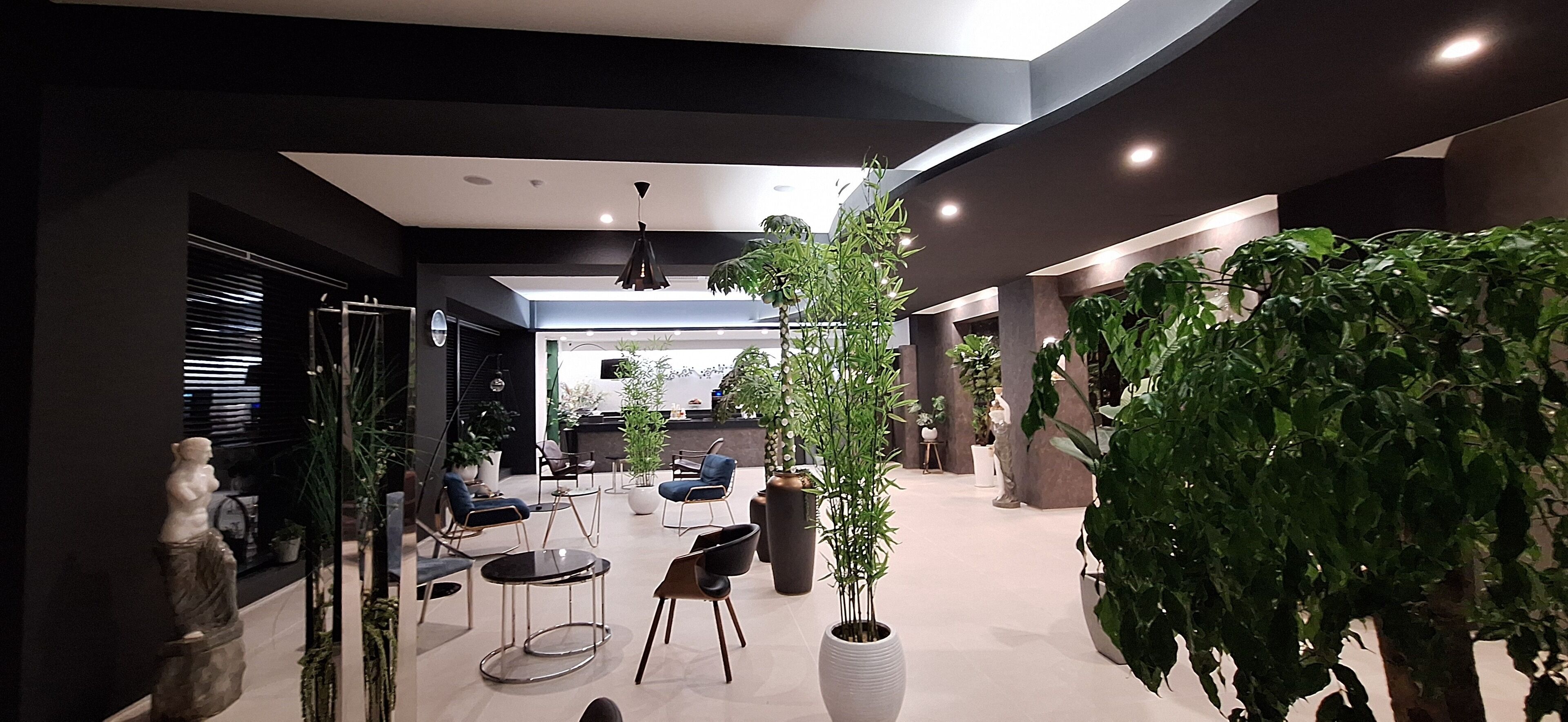 A modern indoor space with seating, plants, and a reception area.