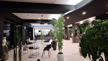 A modern indoor space with seating, plants, and a reception area.