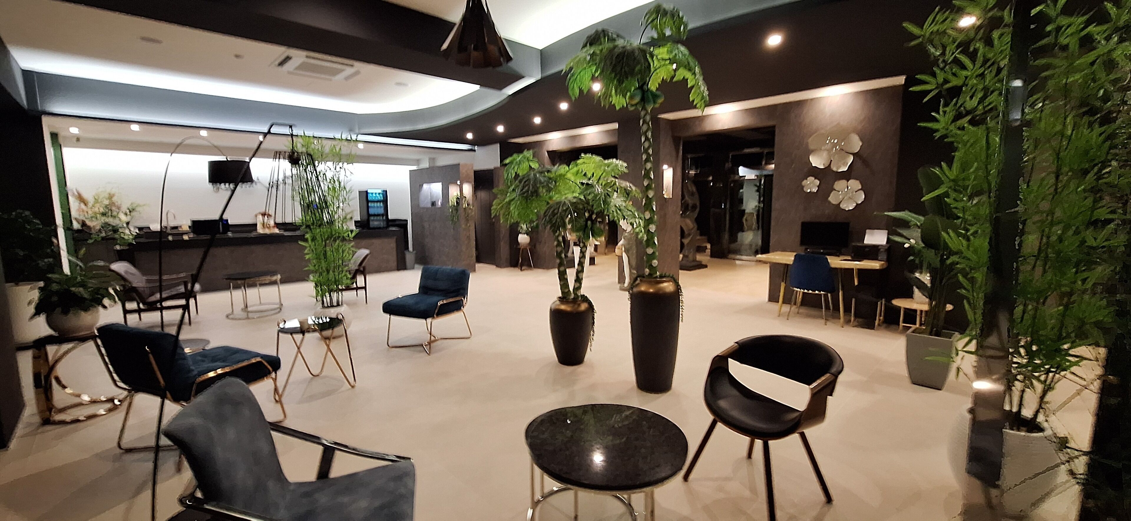 A modern lobby with seating areas, large potted plants, and a reception desk.