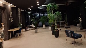 A spacious indoor area with a high ceiling, recessed lighting, and several potted plants.