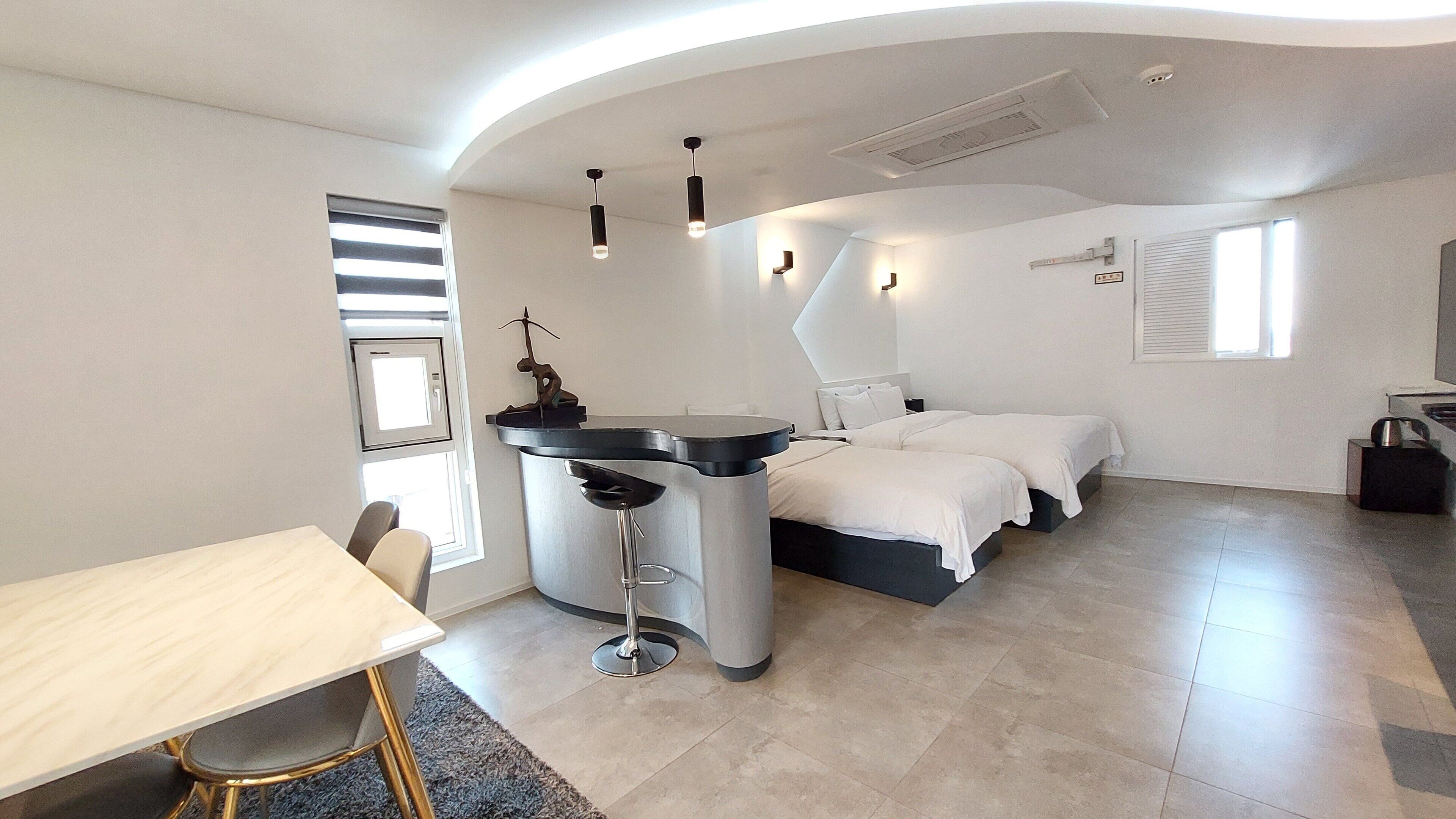 Habitación de hotel compacta con cama, escritorio y una pequeña kitchenette.