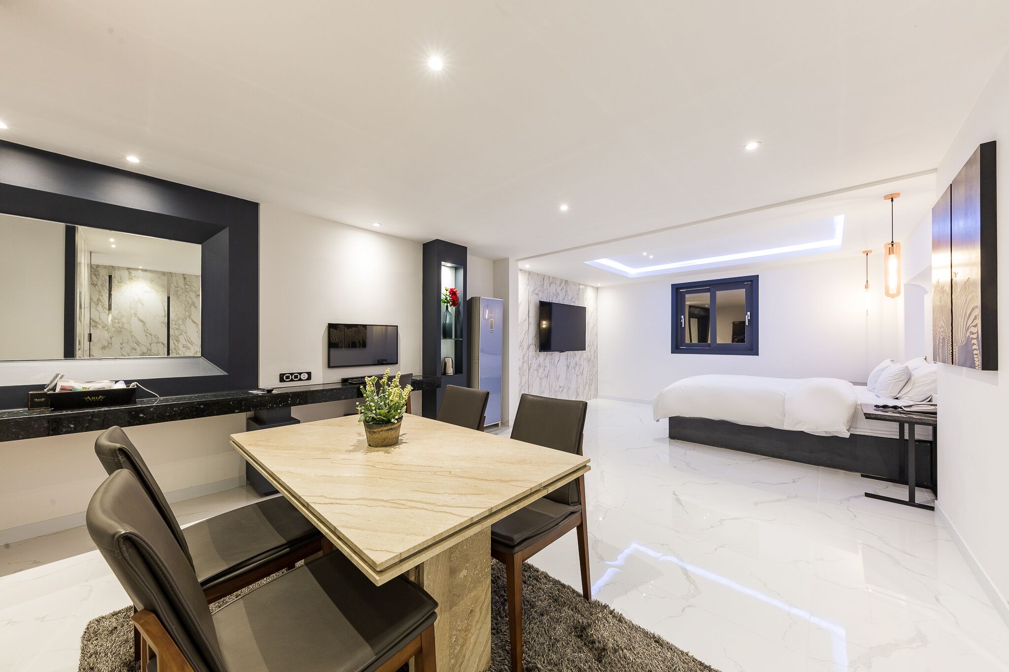 Une chambre d’hôtel moderne équipée d’un coin repas, d’un lit et d’une télévision.