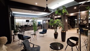 A modern interior with seating areas, large potted plants, and a reception desk.