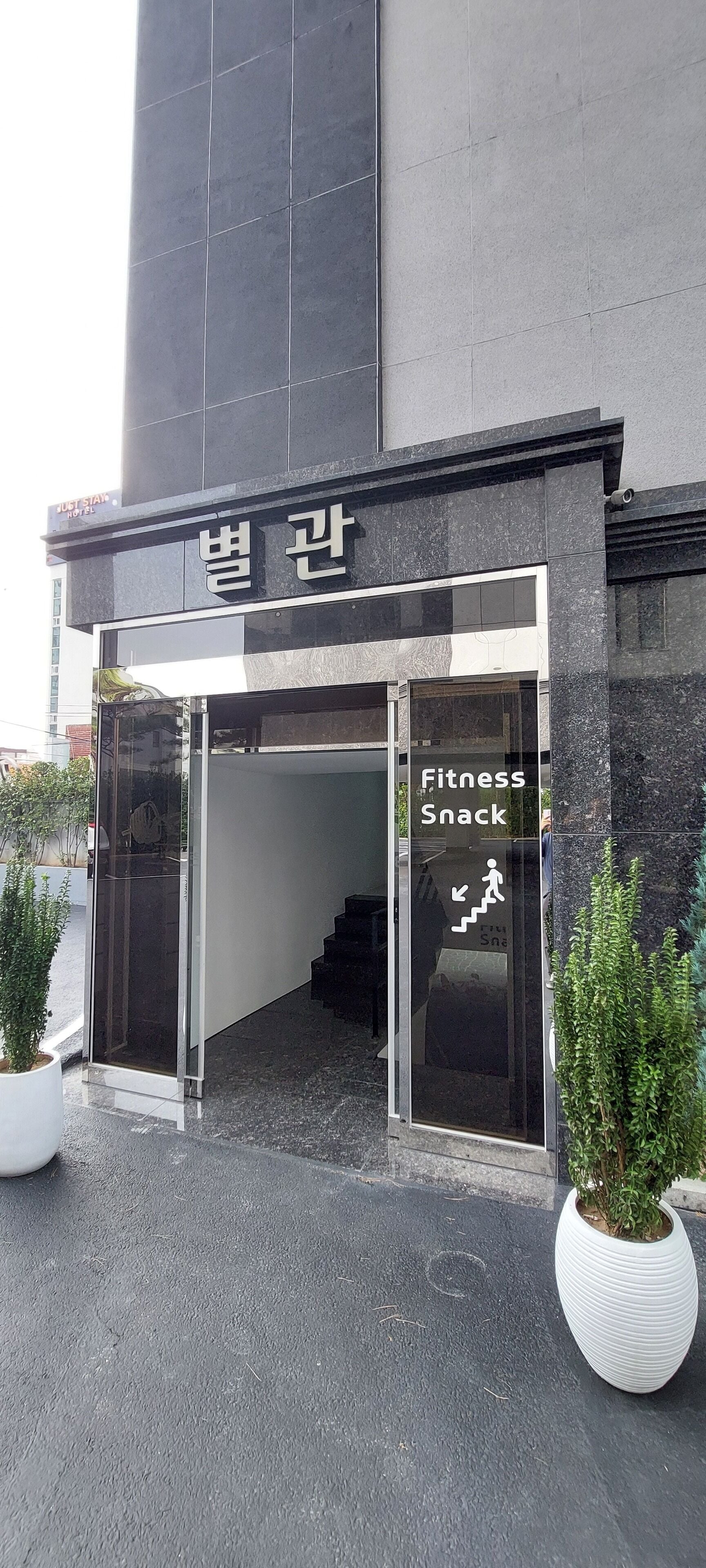 A building entrance with a sign for 'Fitness Snack' and a staircase leading inside.