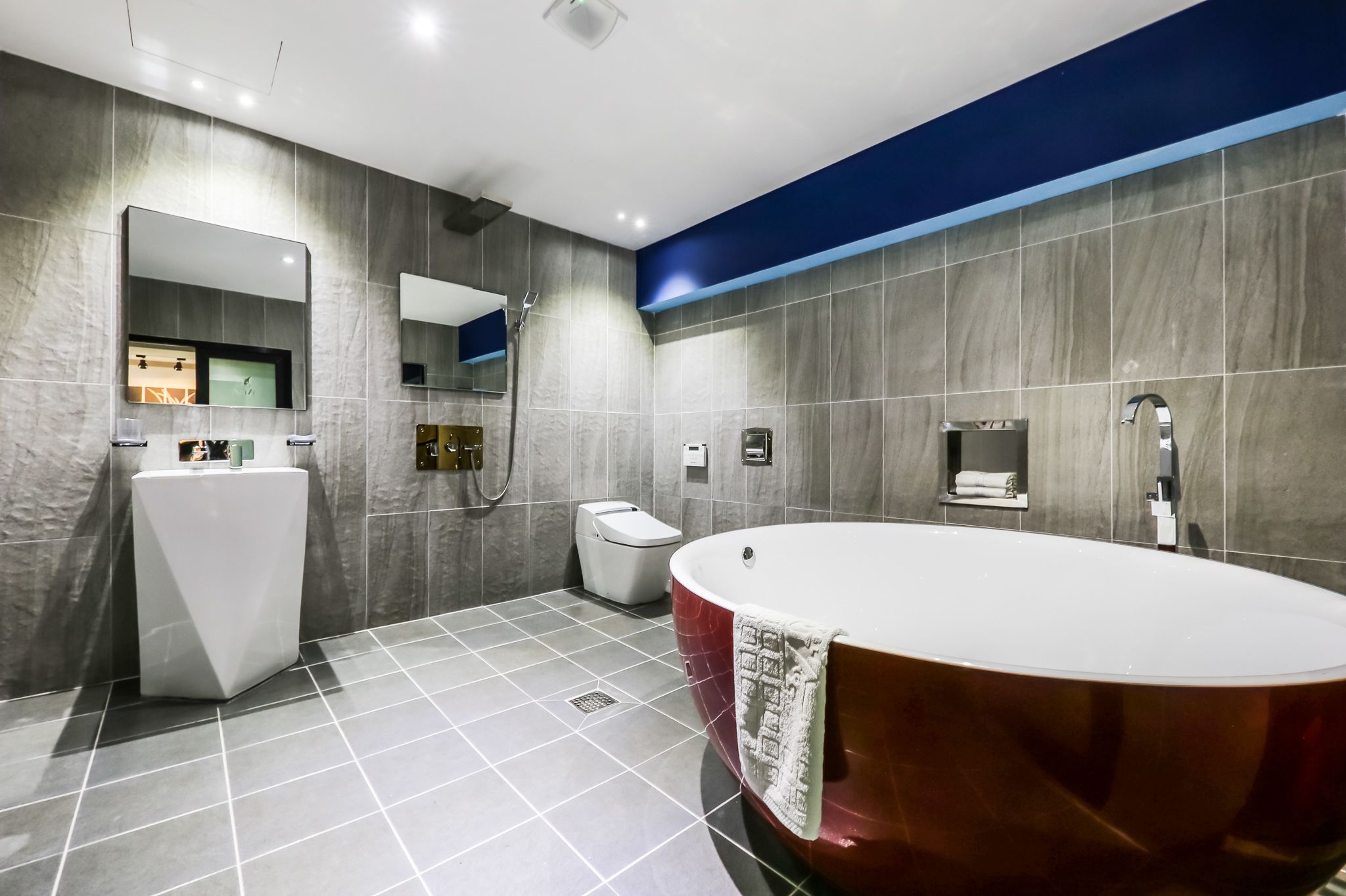 A modern bathroom with a large bathtub, a standalone sink, and a toilet.
